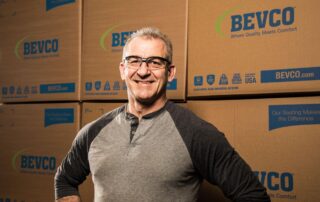 Bevco employee smiling standing in front of boxes