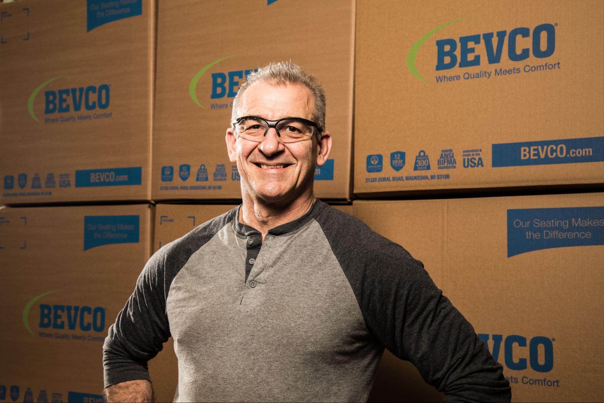 Bevco employee smiling standing in front of boxes