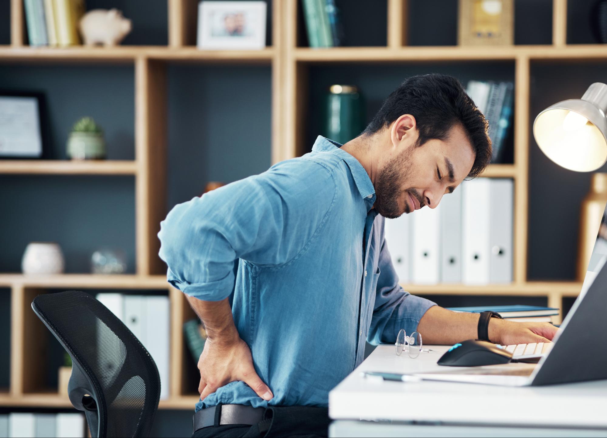 man wincing in pain at his uncomfortable chair
